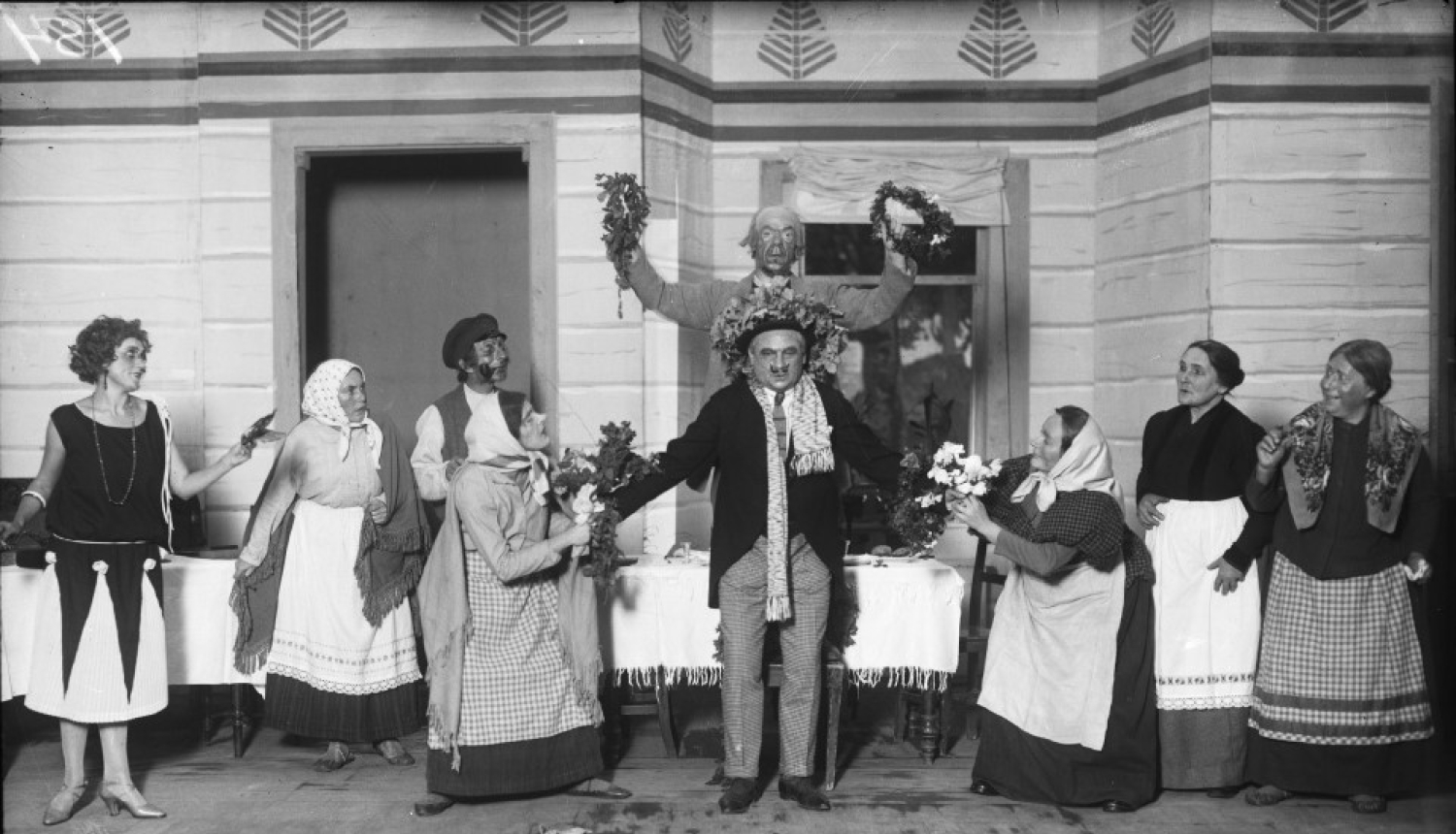 Aina no A. Saulīša komēdijas “Inteliģenti” uzveduma Nacionālā teātra aktieru izpildījumā. No kreisās: 1. Anta Klints - Adelīnas lomā, 6. Alfrēds Amtmanis-Briedītis - Fēliksa Šmigas lomā, 8. Berta Rūmniece - Vēsmiņas mātes lomā, 9. Ella Jēkobsone - Salmienes lomā. Rīga, 1925.gads. Autors nav zināms. Latvijas Valsts kinofotofonodokumentu arhīvs, LNA_KFFDA_F1_9_154