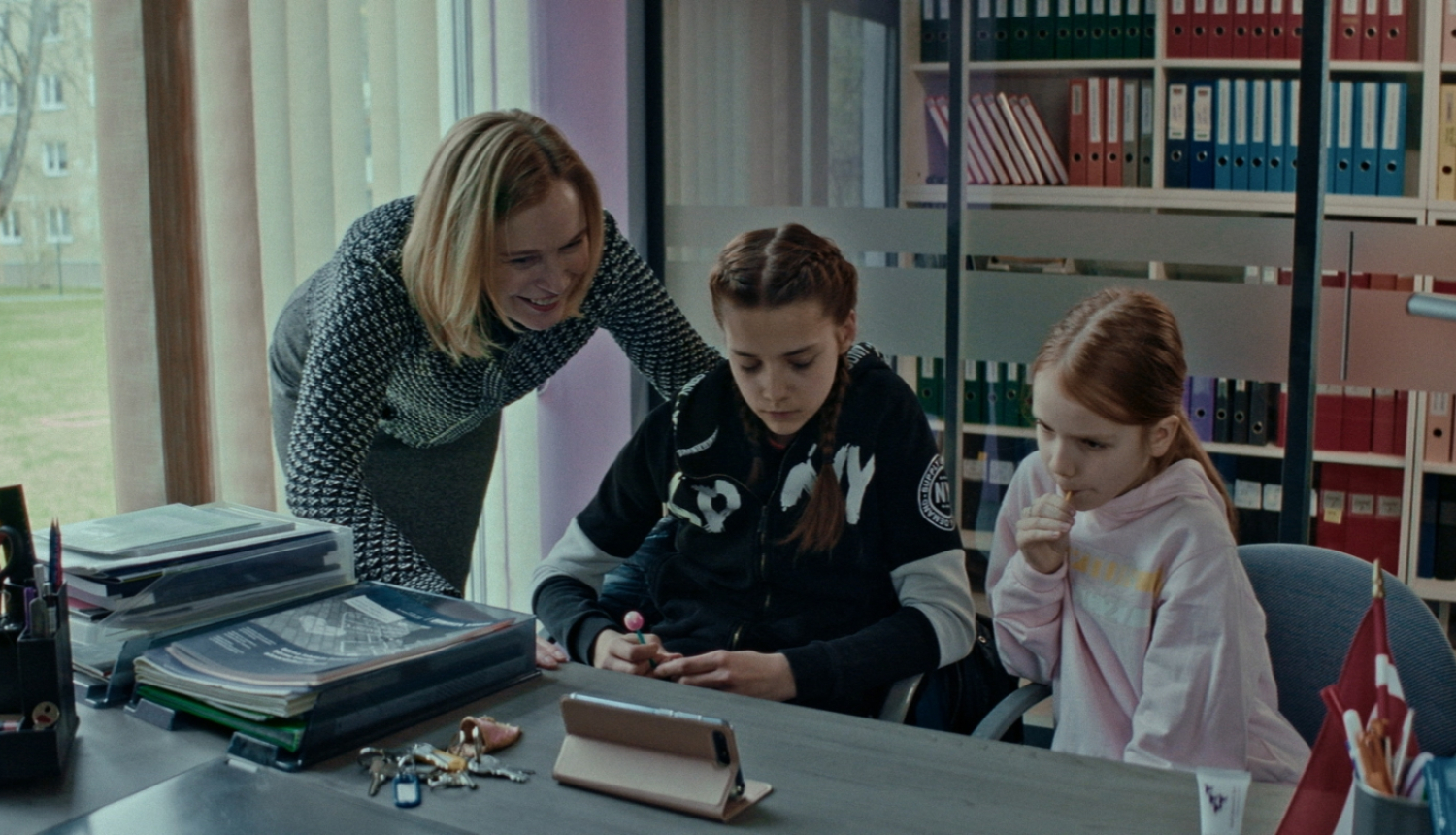 Sieviete un divas meitenes pie galda