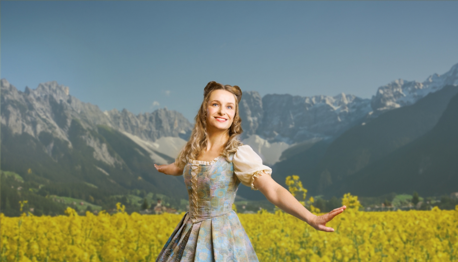 Aktrise uz kalnu fona ziedošā pļavā