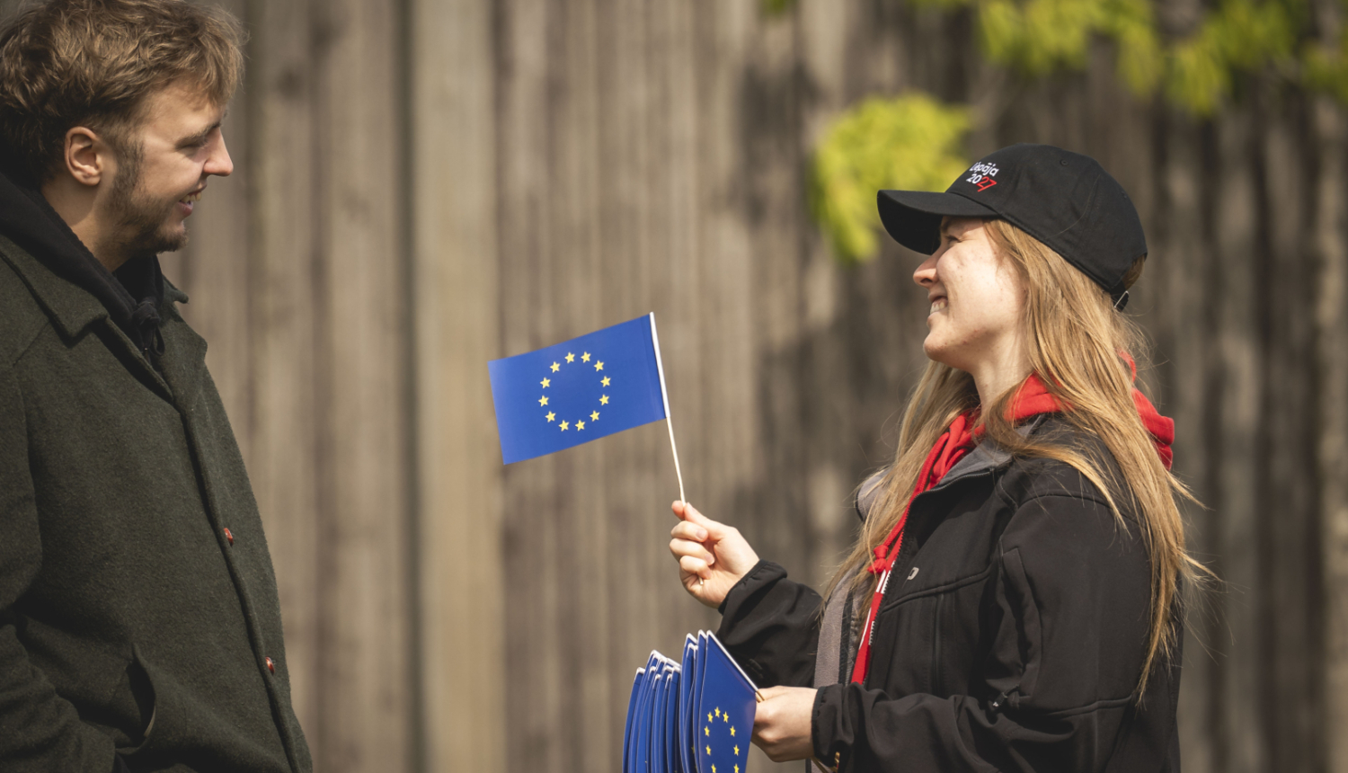 Divi cilvēki, vienam rokās Eiropas Savienības karodziņš