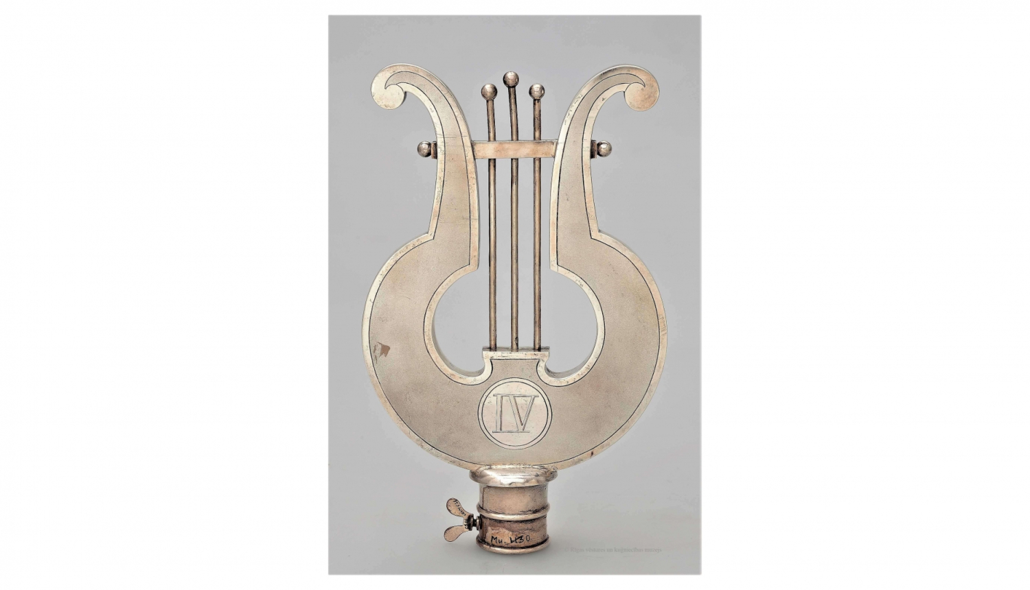 IV vispārējo latviešu dziesmu un mūzikas svētku (Jelgavā) dziesmu kara pirmā godalga – karoga kāta uzgalis, 1895. gads. Saņēmis Rīgas latviešu dziedāšanas biedrības jauktais koris. Izgatavojis meistars Ēriks Bakstats. RVKM krājums.