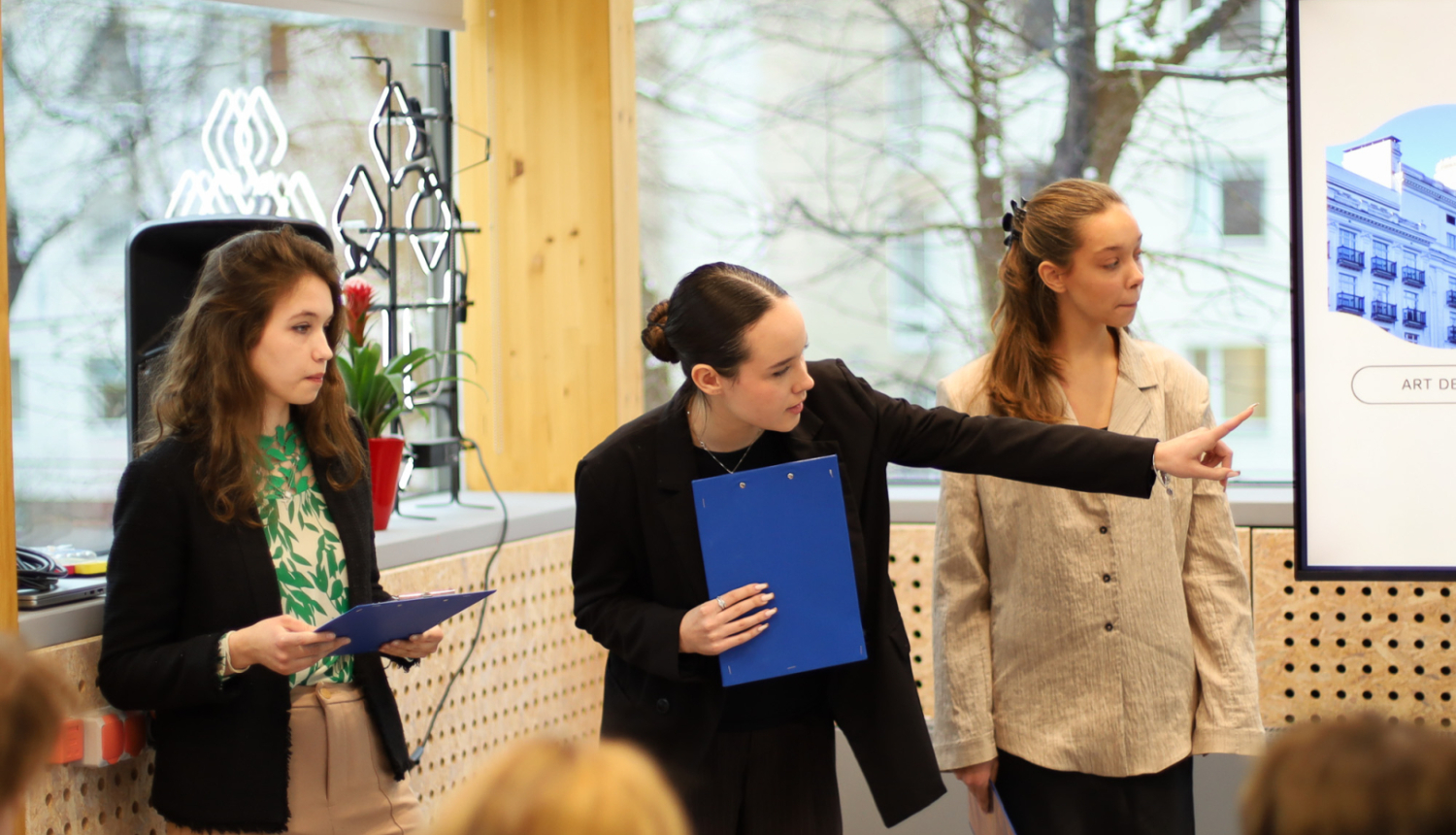 Trīs jaunietes prezentē projektu auditorijas priekšā