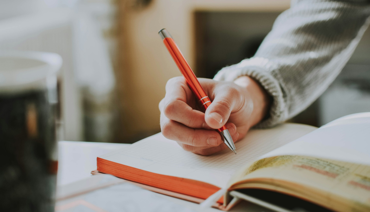 Mācību process, persona pie galda raksta pierakstu kladē