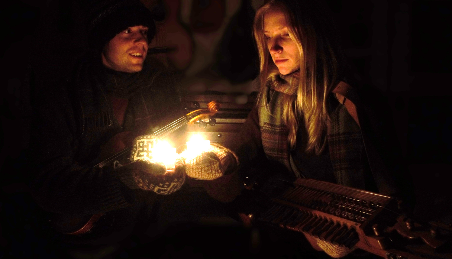 Cilvēki ziemas naktī pie aizdegtas laternas