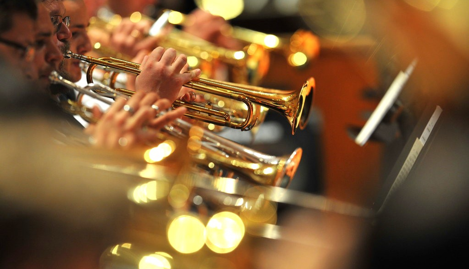 Orķestra dalībnieki pūšaminstrumentu grupā spēlē koncertā
