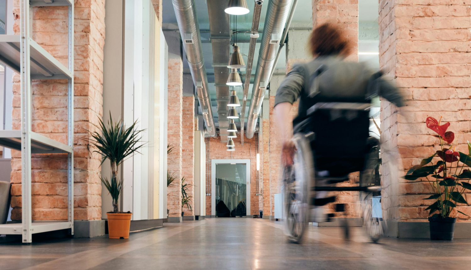 Persona ar invaliditāti ratiņkrēslā, pārvietojoties pa gaiteni
