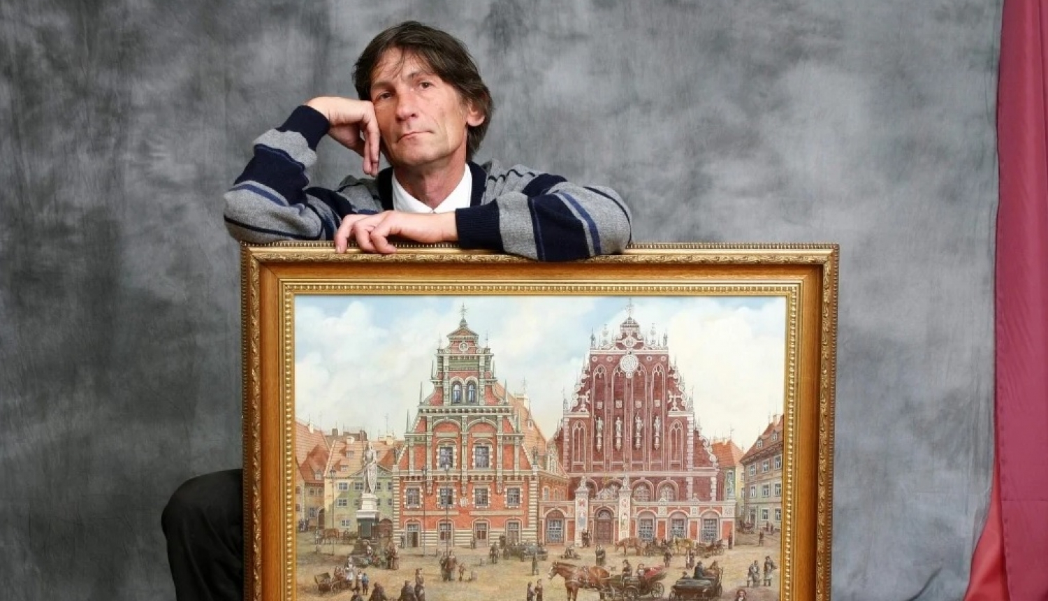 Mākslinieks Sergejs Zinovjevs ar gleznu no izstādes “Mana Rīga”