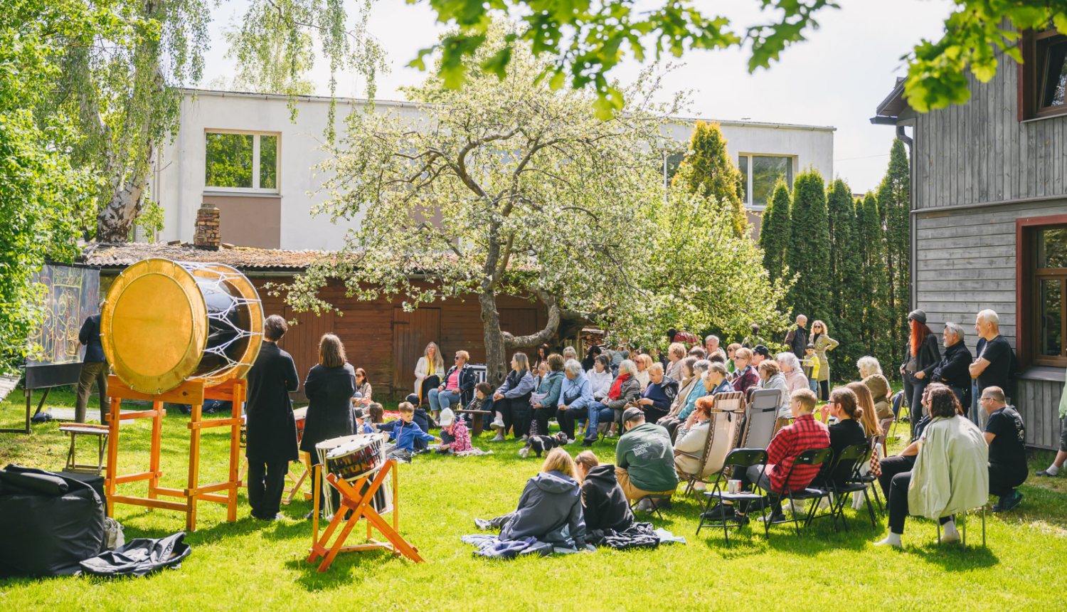 Kopienu programmas pasākums kādā pagalmā starp mājām ar pasākuma apmeklētājiem